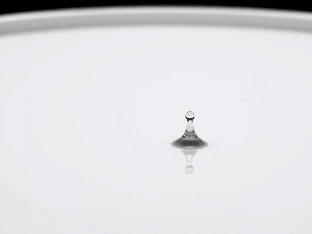 A single water droplet glistening on a surface, reflecting light, conveying intense hydration and purity.
